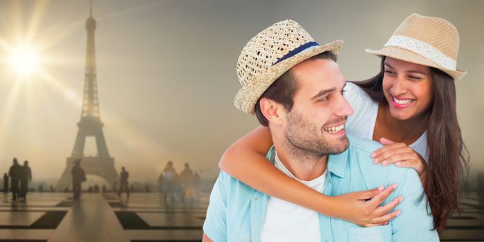 Happy casual man giving pretty girlfriend piggy back against eiffel tower