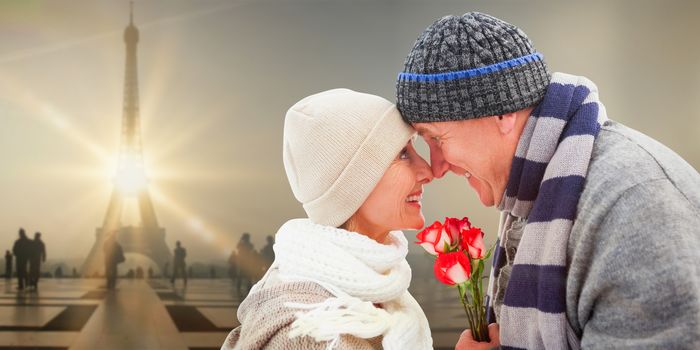 Happy mature couple in winter clothes with roses against eiffel tower