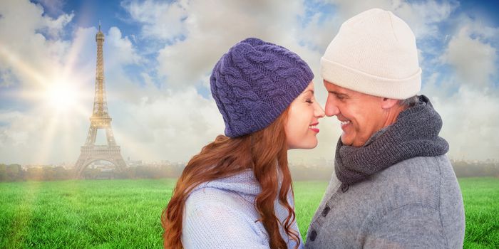 Couple in warm clothing facing each other against eiffel tower