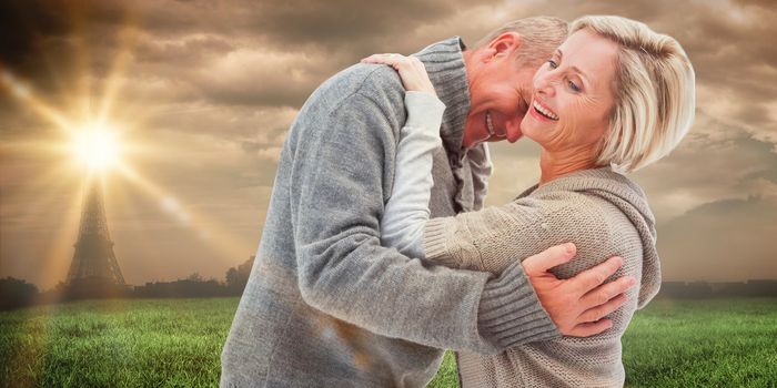 Happy mature couple in winter clothes against paris under cloudy sky