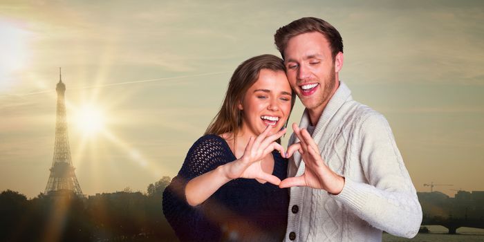 Happy couple forming heart with hands against eiffel tower