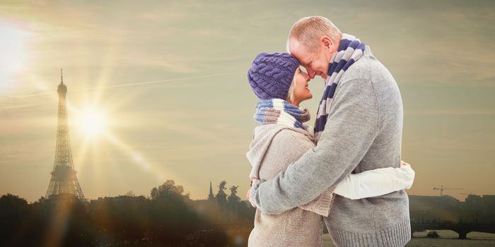 Happy mature couple in winter clothes hugging against eiffel tower