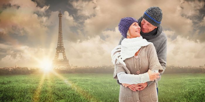 Happy mature couple in winter clothes embracing against paris under cloudy sky