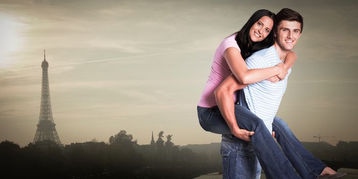 Young man giving girlfriend a piggyback ride against eiffel tower