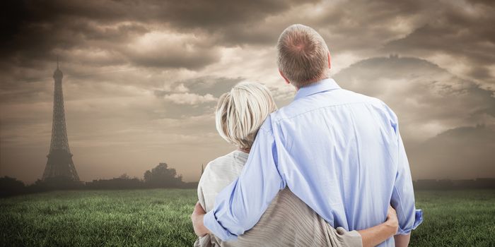 Mature couple hugging and looking against paris under cloudy sky
