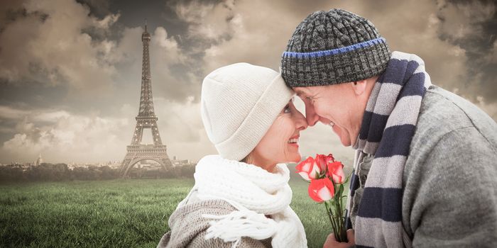 Happy mature couple in winter clothes with roses against paris under cloudy sky