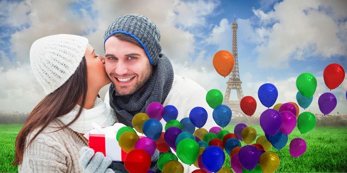 Winter couple holding gift against eiffel tower