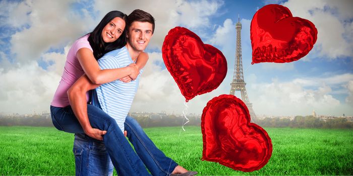 Young man giving girlfriend a piggyback ride against eiffel tower