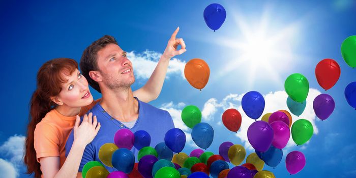 Happy couple looking upwards against bright blue sky with clouds