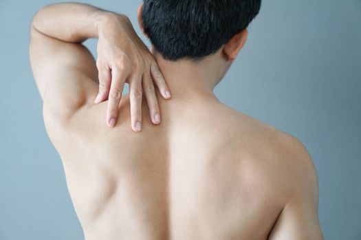 Closeup man hand holding shoulder with pain on blue background, health care and medical concept