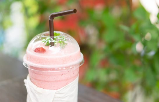 Closeup  strawberry smoothie with green nature background, selective focus