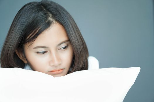 Closeup woman holding pillow sitting on bed in the bedroom with depressed feeling, selective focus