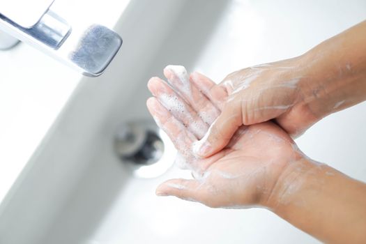 Closeup woman's hand washing with soap in bathroom, selective focus