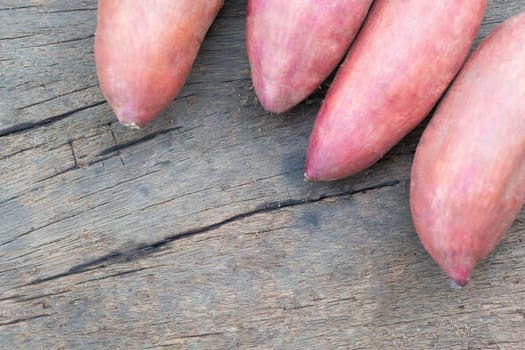 Raw sweet potato on wood table, healthy food concept