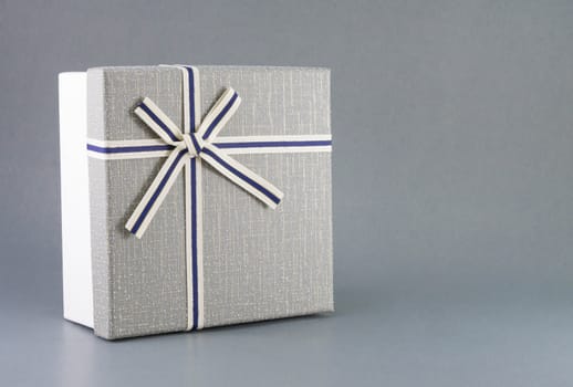 Grey gift box with ribbon on grey background, copy space