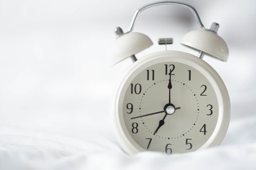 Alarm clock on white bad with light from window, selective focus