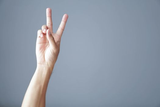 Man hand show V sign with blue background with copy space