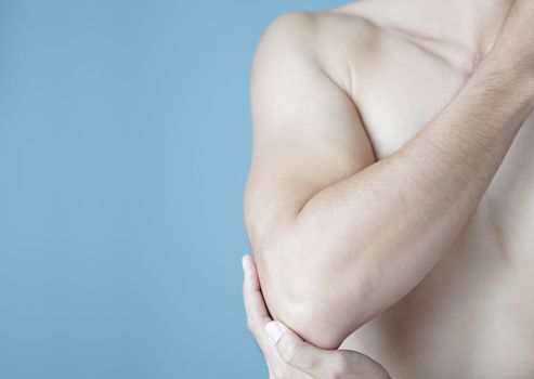 Closeup man hand holding elbow with pain with blue background, health care and medical concept