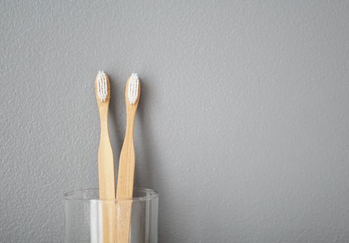 Close up wooden toothbrush in glass with grey background, selective focus