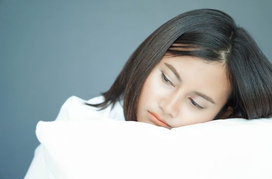 Closeup woman holding pillow sitting on bed in the bedroom with depressed feeling, selective focus 