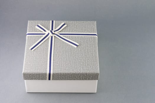 Grey gift box with ribbon on grey background, copy space