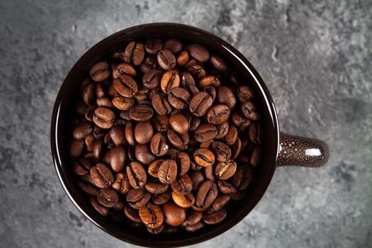minimalism composition of a round brown ceramic Cup with coffee beans on a gray concrete background