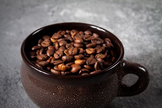 minimalism composition of a round brown ceramic Cup with coffee beans on a gray concrete background