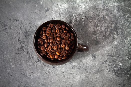 minimalism composition of a round brown ceramic Cup with coffee beans on a gray concrete background