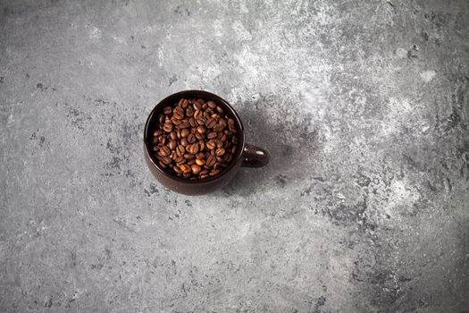 minimalism composition of a round brown ceramic Cup with coffee beans on a gray concrete background