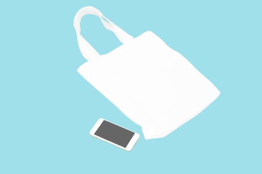 Closeup white bag canvas fabric with smartphone isolated on blue background, Save the world concept