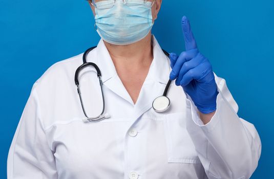 female doctor raised the index finger of his left hand, attention gesture, blue background