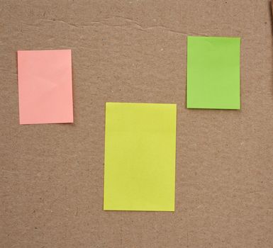blank pink, yellow and green papers glued on a brown cardboard surface. Design template.