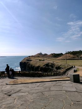 Meandering paths near ocean in jeju island, south korea with blue water and dust roads.