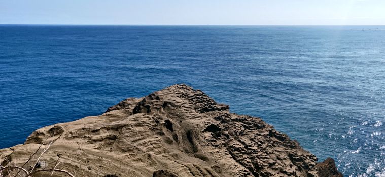 Onlooking blue ocean from a rocky dusty cliff in daylight in jeju Island, South Korea