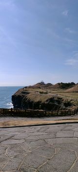 vertical landscape of jeju island, south korea with blue water and meandering paths