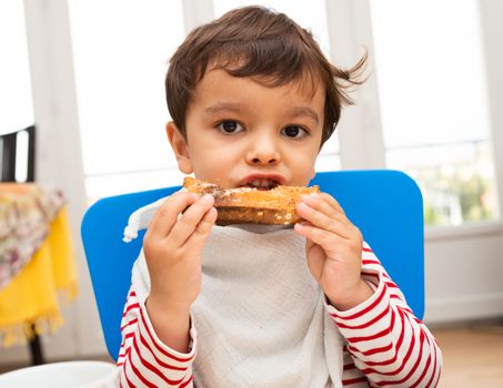 Toddler boy eating a toast with butter