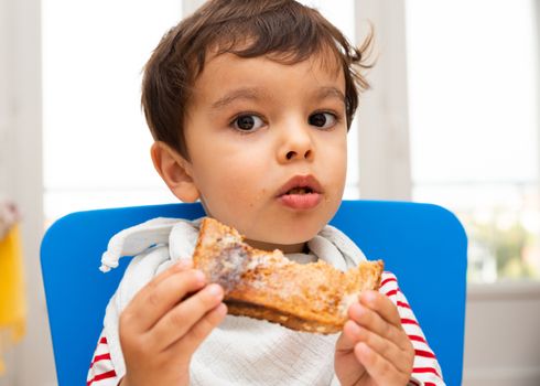 Toddler boy eating a toast with butter