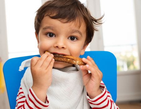 Toddler boy eating a toast with butter