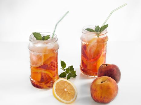Drink with peach and lemon with mint with ice in jars of cold and refreshing with straws delicious and mouth-watering