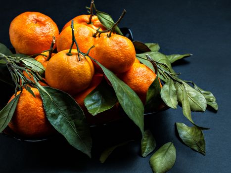 Tasty, fresh, sweet, large orange fruit tangerines with branches and leaves are served to serve on the table for diet and healthy meals for the festive table