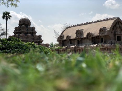 Pancha Rathas is an example of monolith Indian rock-cut architecture. Resembling a chariot ratha, it is carved out of a single, long stone of pink granite. This is one of the Group of Monuments at Mahabalipuram and also a UNESCO World Heritage Site. In this view monuments of Pancha Rathas are beautifully captures from the grass meadow area.