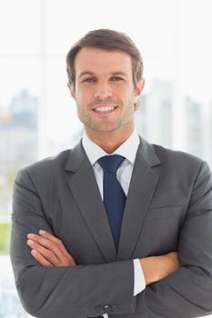Portrait of a young businessman with arms crossed standing over blurred background outdoors
