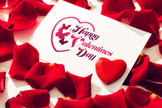 Valentines message against card with red rose petals