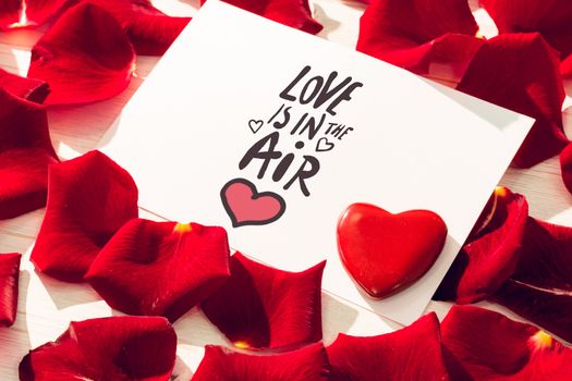 love is in the air against card with red rose petals