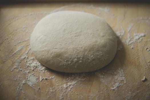 bread dough covered with flour on wooden pastry board