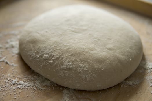 bread dough covered with flour on wooden pastry board