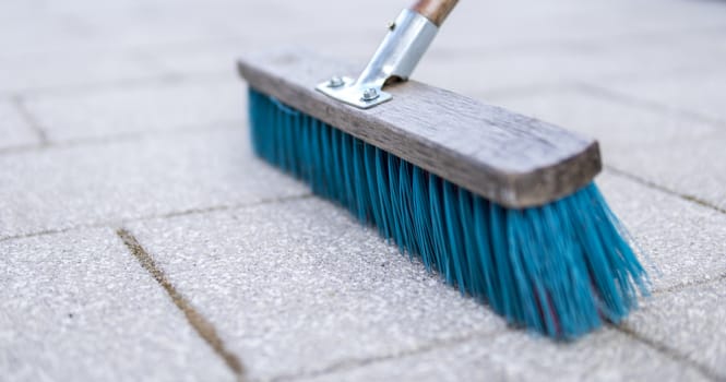 detail of blue brush used for cleaning pavemnet made from concrete stones