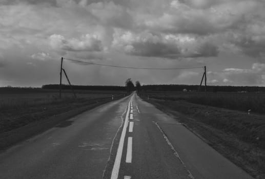 Heavy weather over empty old road with vintage power line poles