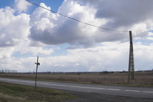 landscape with holy cross and power line pole over dark clouds