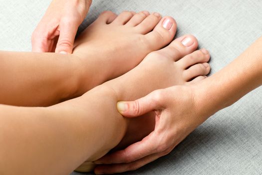 Close up of hands applying pressure on female ankle.Physiotherapist massaging feet with thumbs. 